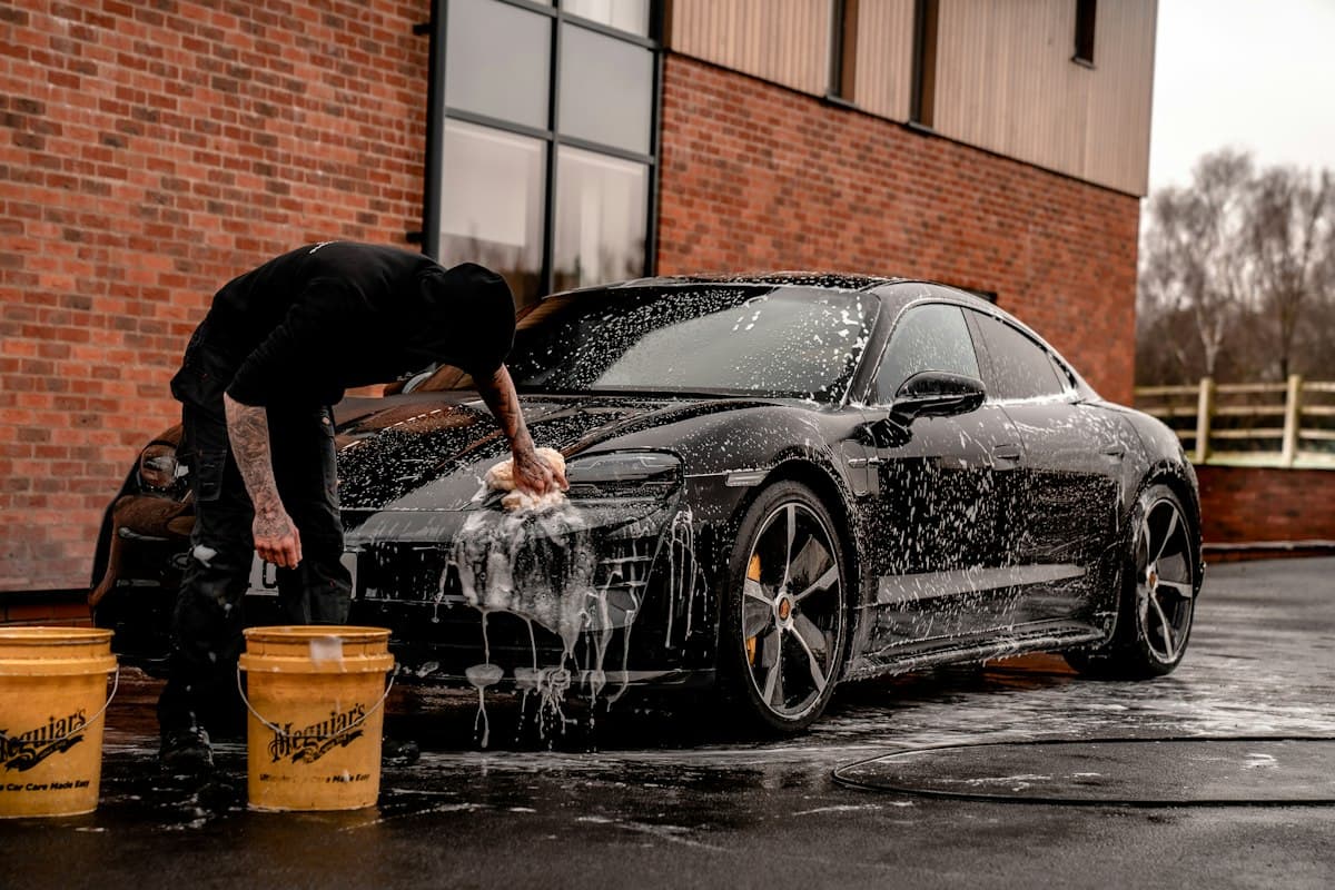 Black coupe being washed, water spraying off the hood